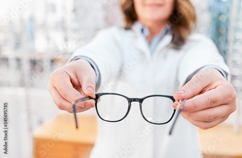 Optician showing and suggesting eyeglasses in optical shop