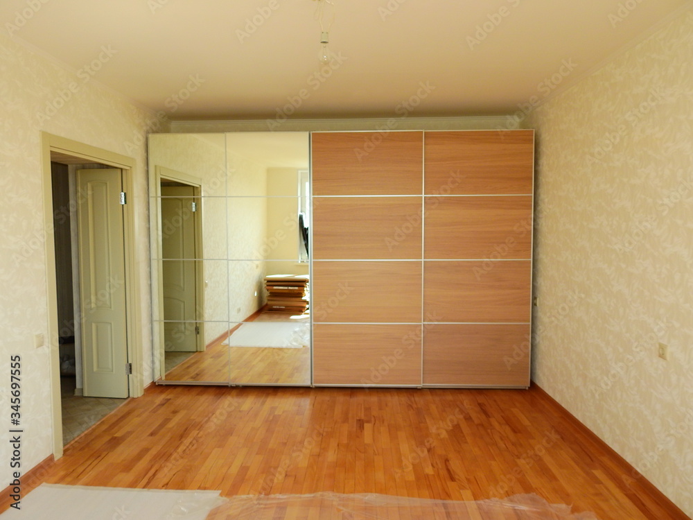Flat pack furniture wardrobe with a mirror installed wall to wall in a