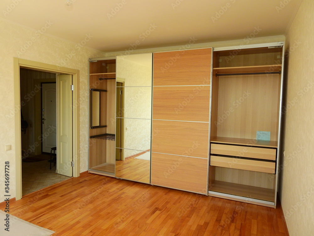 Flat pack furniture wardrobe with a mirror installed wall to wall in a