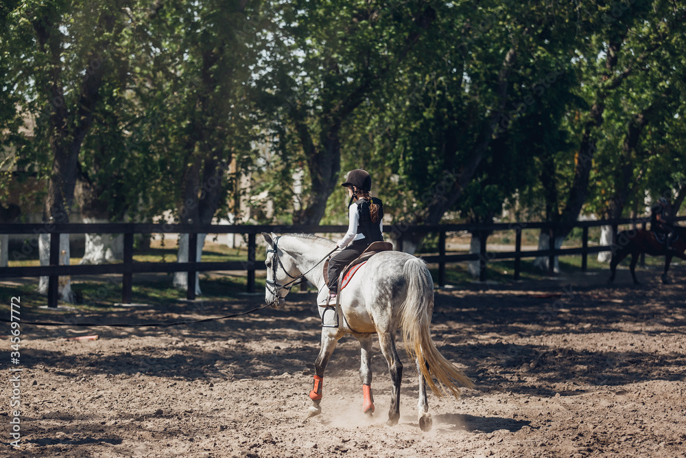 Little Girl in helmet Learning Horseback Riding. Instructor teaches kid Equestrian. Little Girl in helmet Learning Horseback Riding. Instructor teaches kid Equestrian.