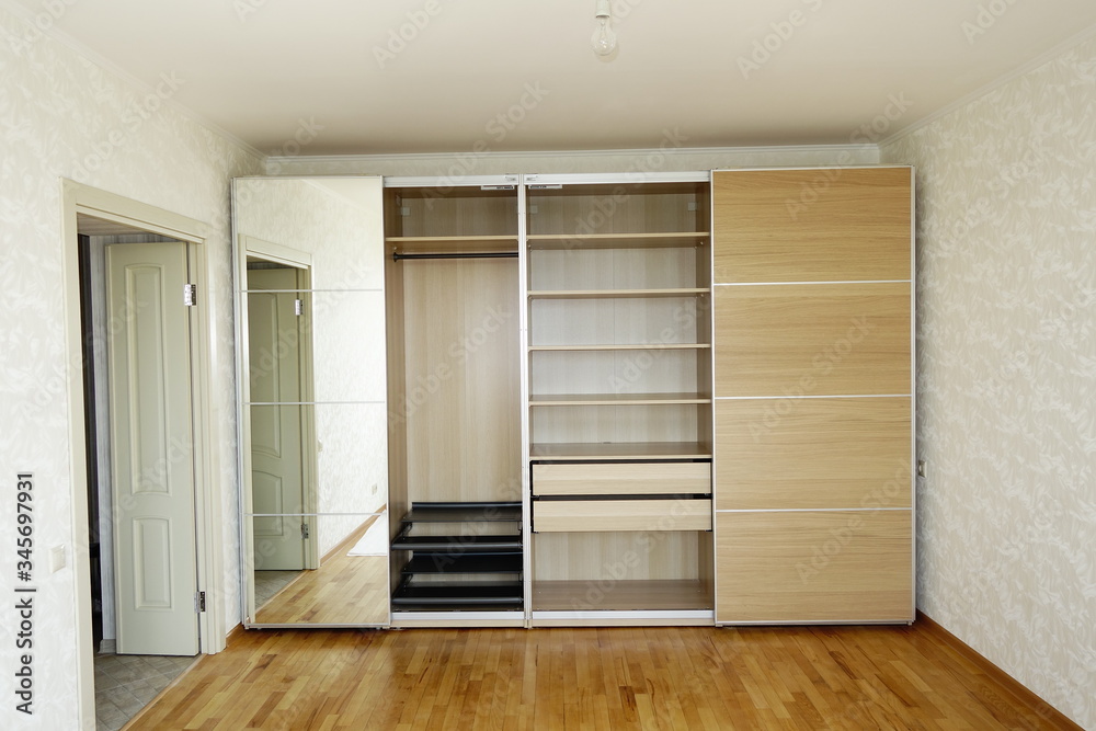 Flat pack furniture wardrobe with a mirror installed wall to wall in a