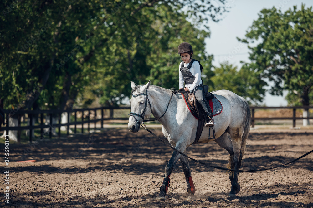 Little Girl in helmet Learning Horseback Riding. Instructor teaches kid Equestrian. Little Girl in helmet Learning Horseback Riding. Instructor teaches kid Equestrian.