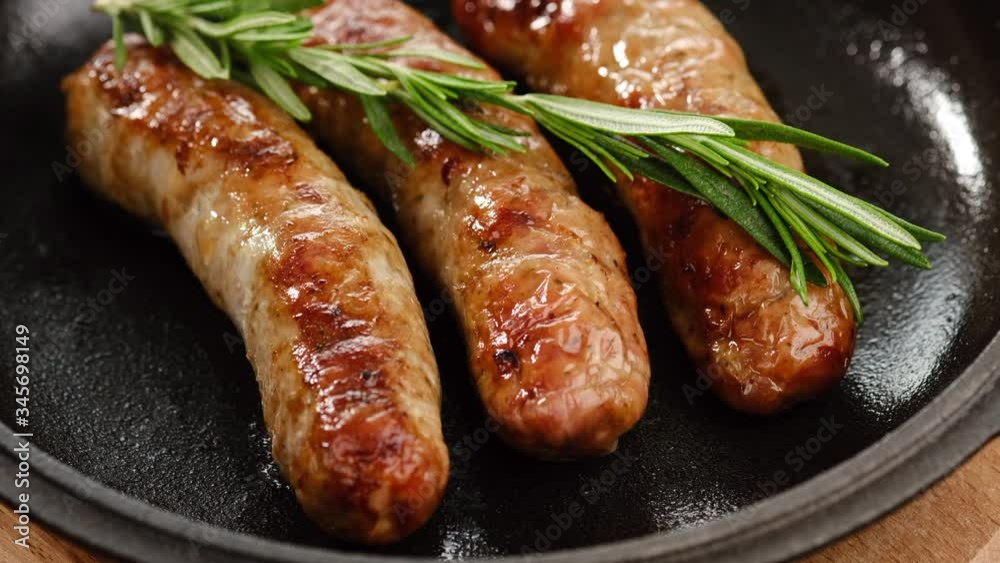 sausages fried on pan with sprig green rosemary, rotation. closeup sausages fried on pan with sprig green rosemary, rotation. closeup