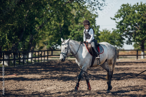 Little Girl in helmet Learning Horseback Riding. Instructor teaches kid Equestrian. © sergiophoto