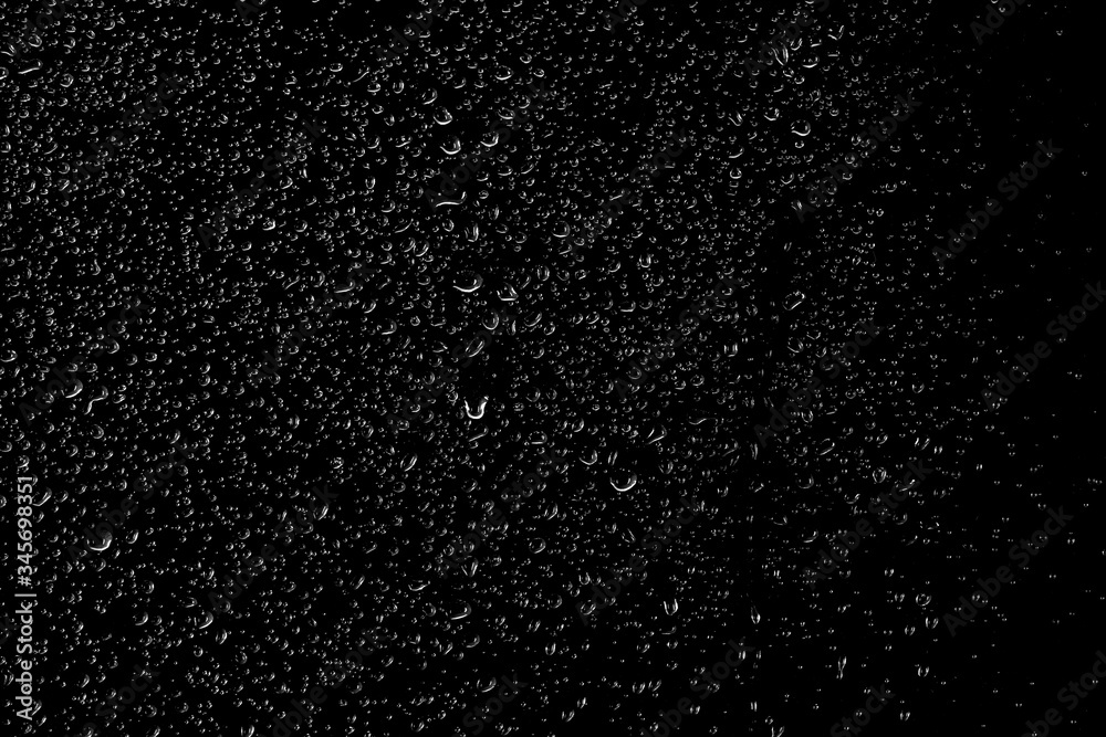 Drops of water flow down the surface of the clear glass on a black background.	
