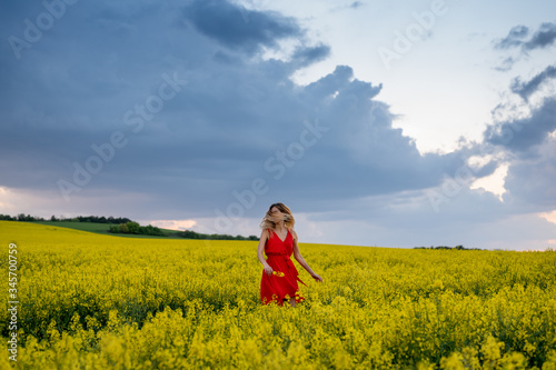 Beautiful blonde model in rapeseed field before storm