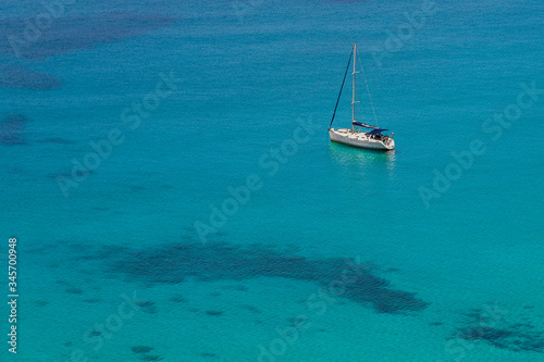A sailing boat anchored in the turquoise Mediterranean Sea. In this wonderful seascape the crew is preparing to take a bath