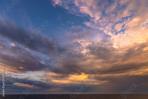 Fototapeta Naklejka Na Ścianę i Meble -  Sunset and dramatic set of clouds drifting over the tropical waters of the Caribbean Sea are lit by the last moments of daylight.