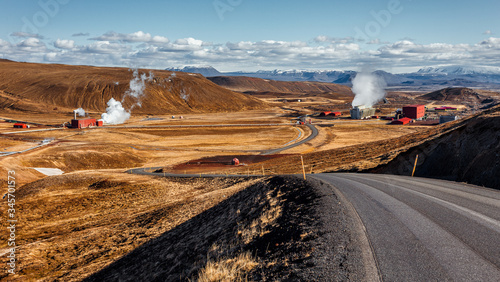 Tipical Icelandic nature landscape. Asphalt road and geothermal power station in th sunny day. Geothermal power plant located North Iceland.