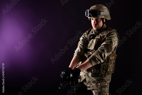 Soldier with gun aims at the target on mission on violet background. Concept of war. photo