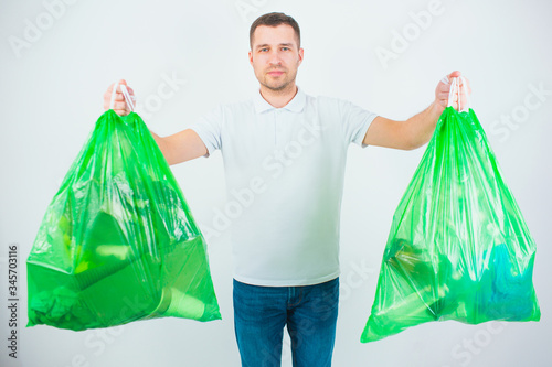Young man isolated over white background. Guy hold two plastic bags with trash and waste inside it. Getting ready for resycling and reusing process. photo
