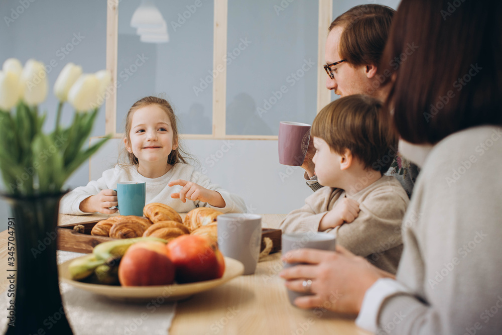 Young happy family with two kids having breakfast together. redheaded dad, kids and brunette mom together in the kitchen.