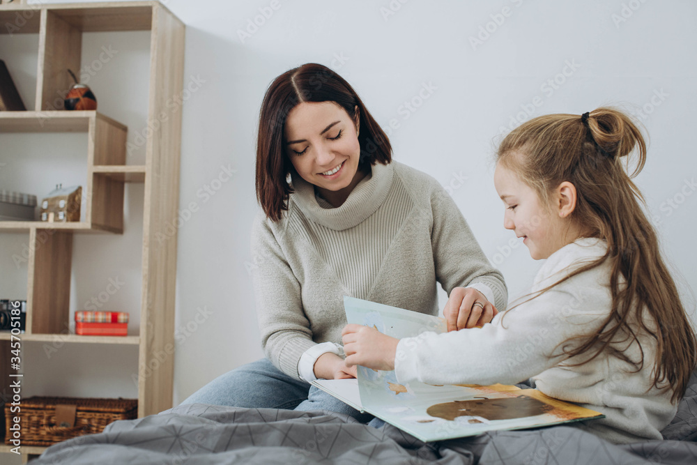 Pretty young mother reading a book to her daughter. Family holiday and togetherness. Pretty young mother reading a book to her daughter. Family holiday and togetherness.