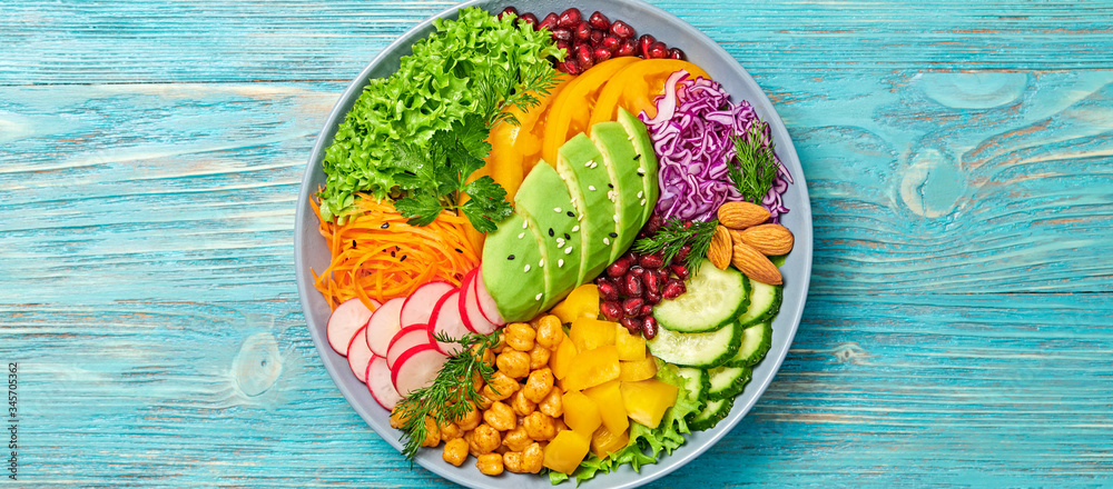 Buddha bowl salad with avocado, tomato, lettuce, cucumber, red cabbage, chickpeas, pomegranate. Vegan and balanced salad concept. Rainbow mix summer salad on wood, banner Buddha bowl salad with avocado, tomato, lettuce, cucumber, red cabbage, chickpeas, pomegranate. Vegan and balanced salad concept. Rainbow mix summer salad on wood, banner