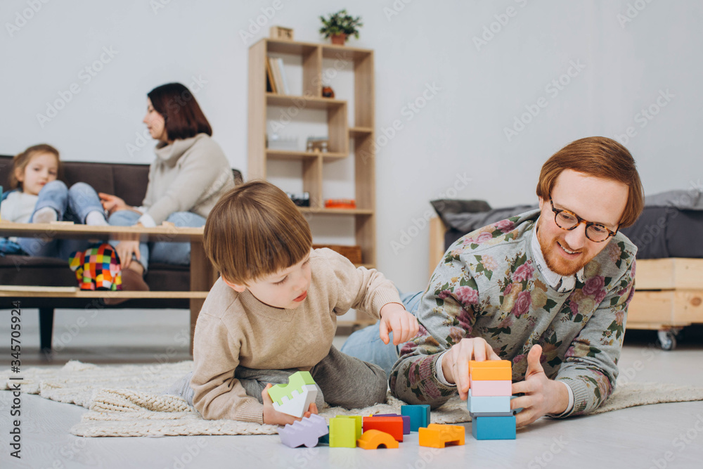 Father in glasses and adorable toddler son building wooden constructor tower. Father in glasses and adorable toddler son building wooden constructor tower.