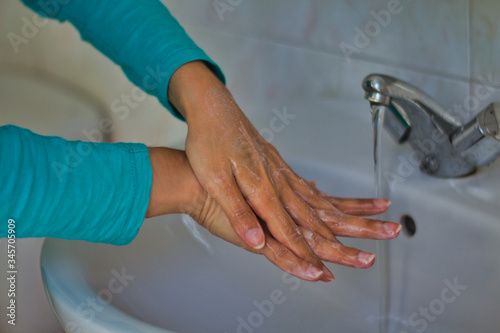 Woman wearing a blue shirt washing her hands with soap © J.J. Martínez