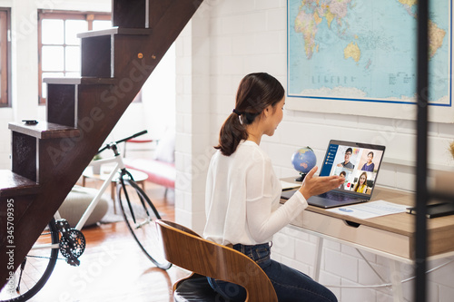 Young Asian businesswoman work at home and virtual video conference meeting with colleagues business people, online working, video call due to social distancing at home office photo
