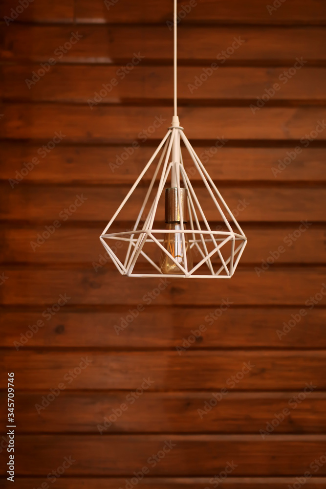 Loft style incandescent white lamp on wood wall background. Modern style home design. selective focus