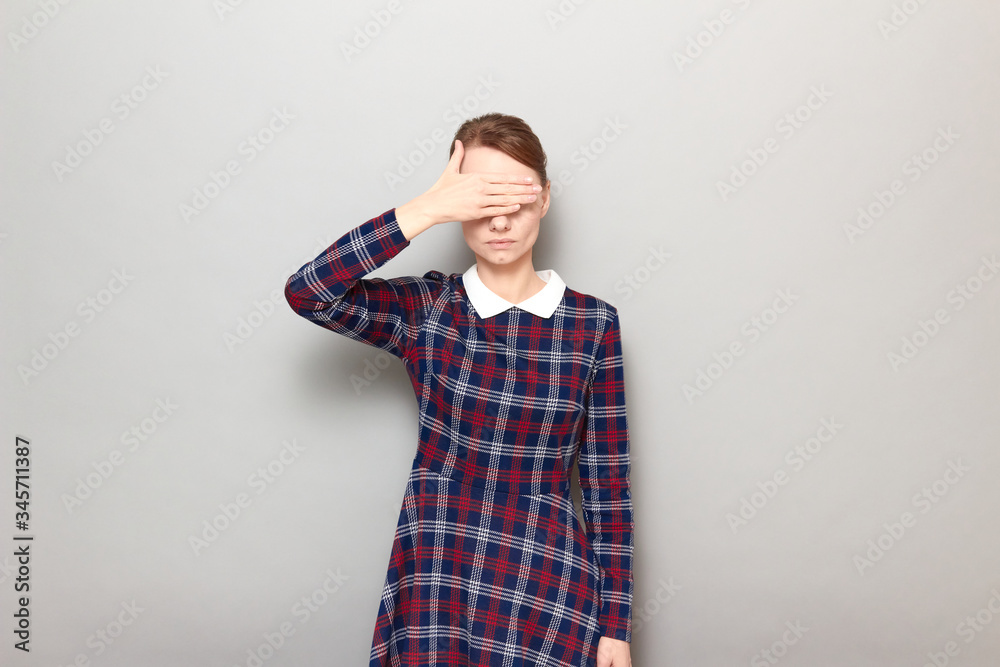 Girl is covering her eyes with hand, not wanting to look at something