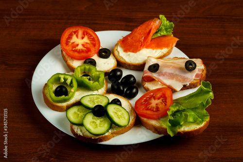 White plate with assorted sandwiches on a wooden table.
