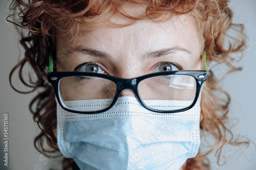 readhead woman with glasses and surgical mask photo