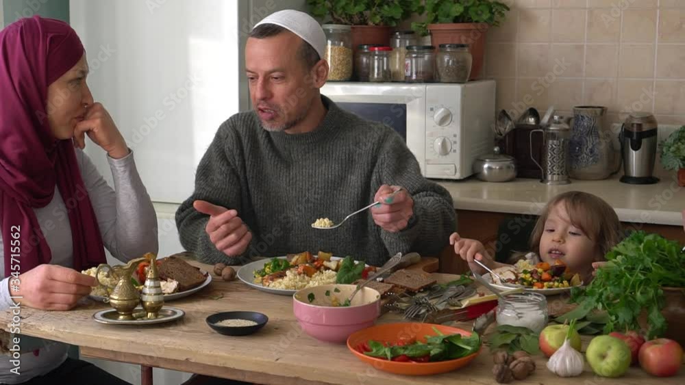 Muslim people are eating. Muslim family have dinner together at the table at home. Ramadan in coronavirus isolation Muslim people are eating. Muslim family have dinner together at the table at home. Ramadan in coronavirus isolation
