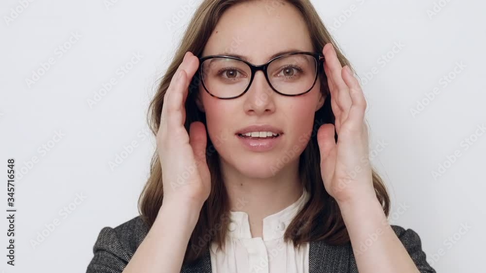Beautiful young businesswoman trying glasses on and checking if it fits while being glad and smiling to the camera Beautiful young businesswoman trying glasses on and checking if it fits while being glad and smiling to the camera