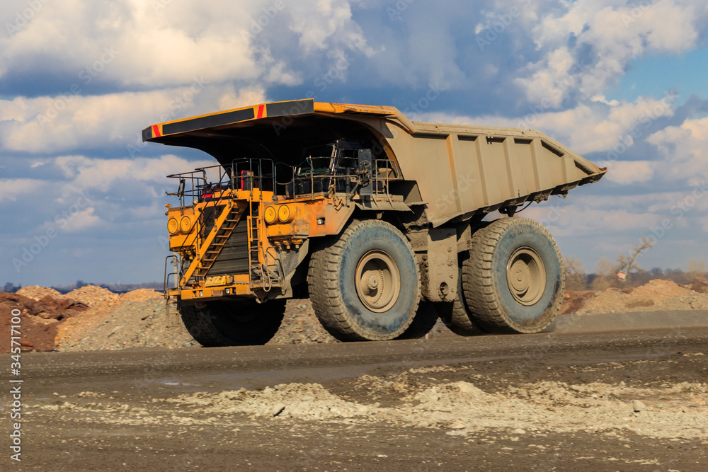 Huge yellow mining dump truck working in iron ore quarry. Mining industry