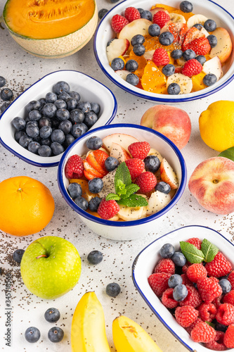 Fresh organic fruit salad with Chia seeds. Healthy breakfast set on grey background. The concept of delicious and healthy food. Top view, copy space