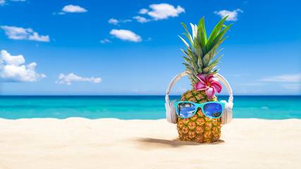 Pineapple with sunglasses and headphones at tropical beach - Holiday Vacation Concept
