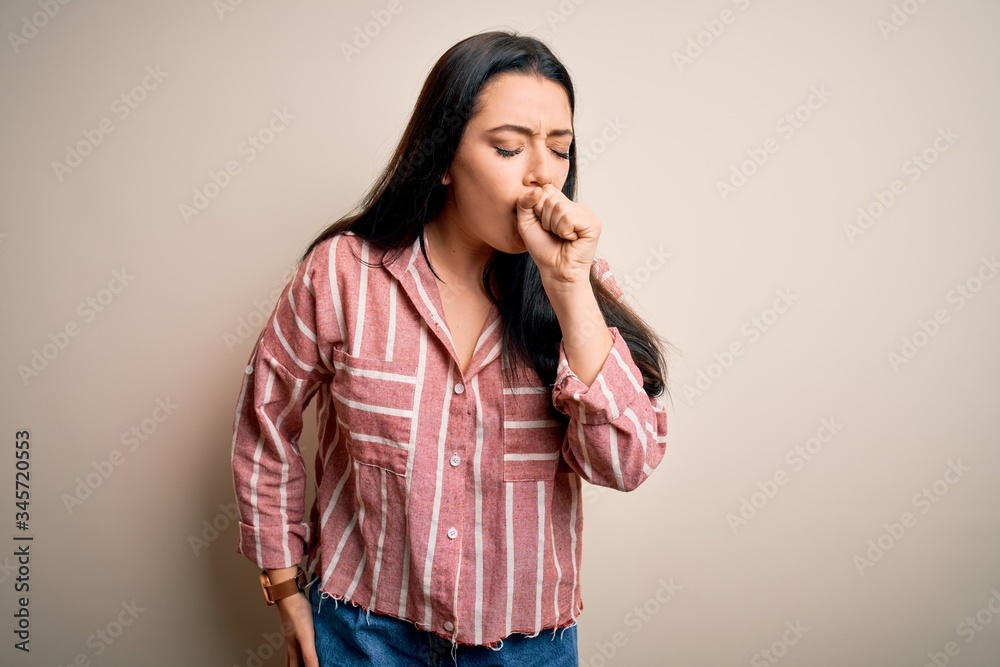 Young brunette woman wearing casual striped shirt over isolated background feeling unwell and coughing as symptom for cold or bronchitis. Health care concept. Young brunette woman wearing casual striped shirt over isolated background feeling unwell and coughing as symptom for cold or bronchitis. Health care concept.