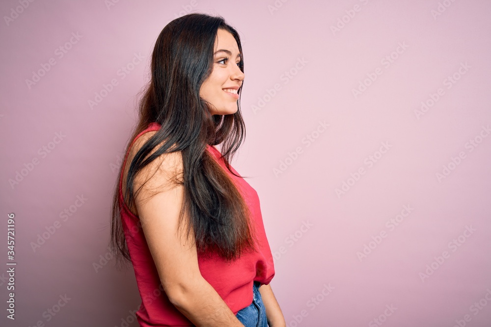 Young brunette woman wearing casual summer shirt over pink isolated background looking to side, relax profile pose with natural face and confident smile.