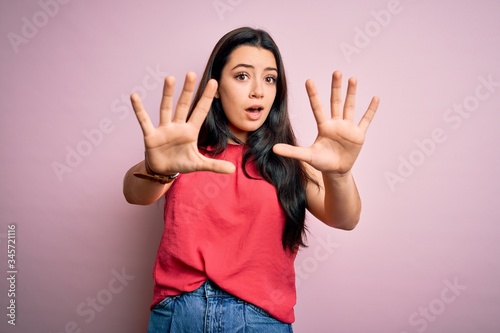 Young brunette woman wearing casual summer shirt over pink isolated background doing stop gesture with hands palms, angry and frustration expression