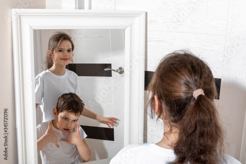 Reflection of a girl in the mirror by two persons. Sister and brother concept. Boy and girl. Concept of Gender dysphoria.
