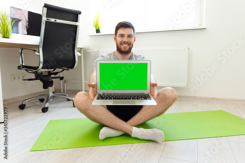 Man Showing Laptop with Green Screen. Man Smilling after Home Sports. Home Sport, Healthy Life, Quarantine Concept. Man Sitting