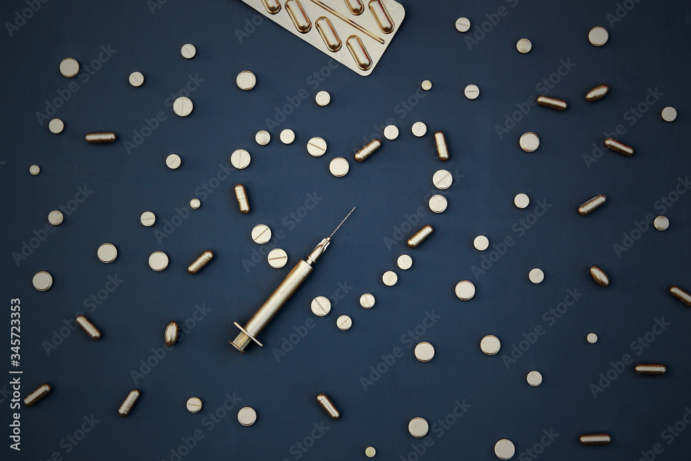 Gold tablets and syringes on a dark background. Gold tablets and syringes on a dark background.