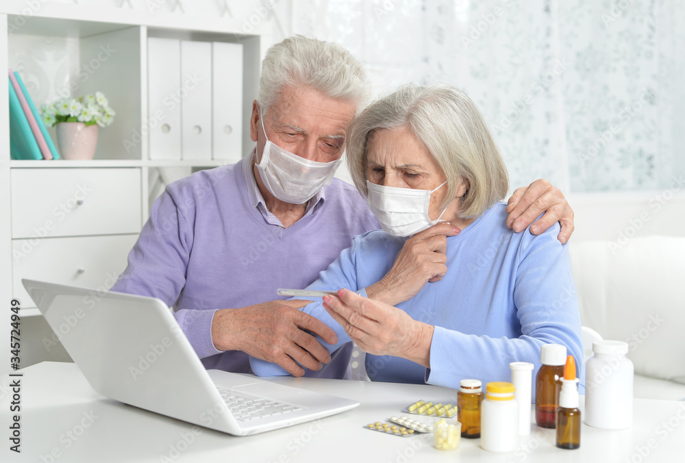 Ill senior couple with facial masks using laptop Ill senior couple with facial masks using laptop