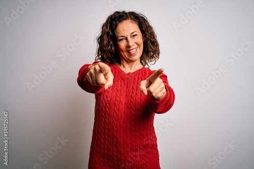 Middle age brunette woman wearing casual sweater standing over isolated white background pointing to you and the camera with fingers, smiling positive and cheerful