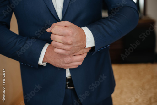 Stylish young man buttoning the cuff links on the sleeves. Style