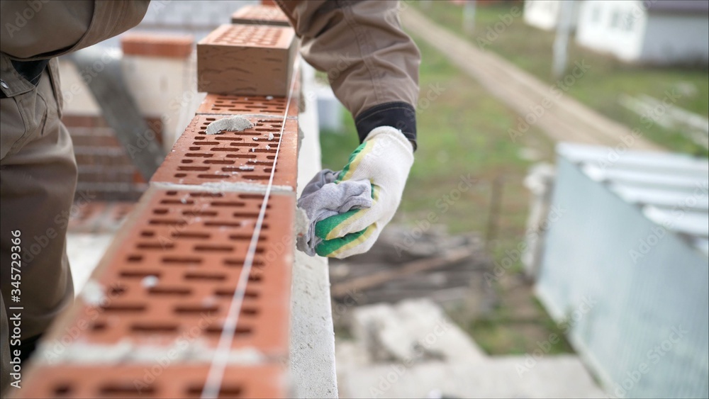 Worker wipes the seams in the brickwork. Worker rewrites a brick wall. Brick house construction Worker wipes the seams in the brickwork. Worker rewrites a brick wall. Brick house construction