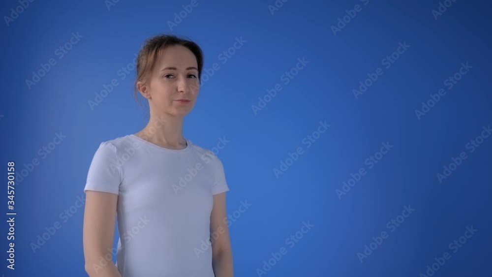 Slow motion: portrait of woman putting on medical face mask and looking at camera in room with blue wall at home. Self isolation, prevention, quarantine, COVID19, coronavirus, safety concept Slow motion: portrait of woman putting on medical face mask and looking at camera in room with blue wall at home. Self isolation, prevention, quarantine, COVID19, coronavirus, safety concept