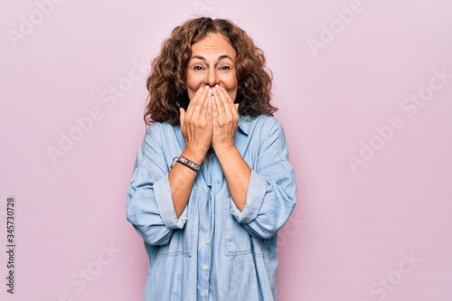 фотографія Middle age beautiful woman wearing casual denim shirt standing over pink backgro