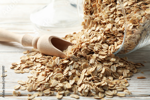 Glass jar with oatmeal and scoop on wooden background, close up