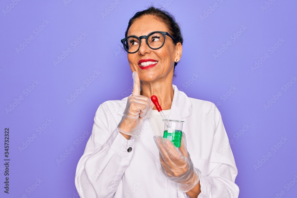 Middle age senior scientist woman wearing laboratory coat holding research test tube serious face thinking about question, very confused idea Middle age senior scientist woman wearing laboratory coat holding research test tube serious face thinking about question, very confused idea