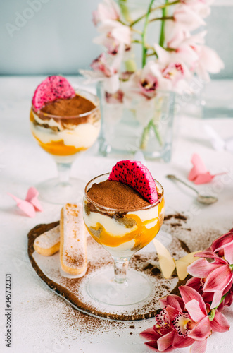 Tiramisu creme dessert with mango in a glass. Dessert and orchid decoration on the table