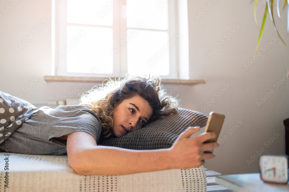 Obraz premium Young woman using smartphone in bed 