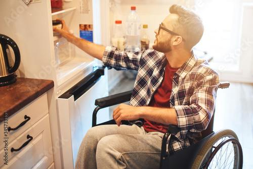Handicapped man sitting with open fridge