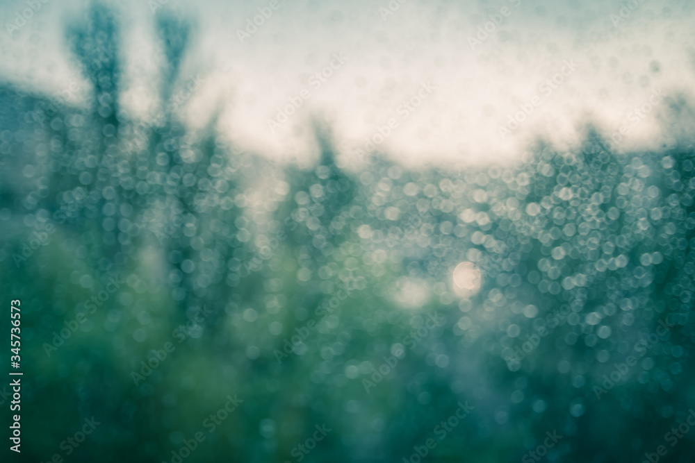 Bokeh defocused rain on the glass. Green trees and buildings in the background Bokeh defocused rain on the glass. Green trees and buildings in the background