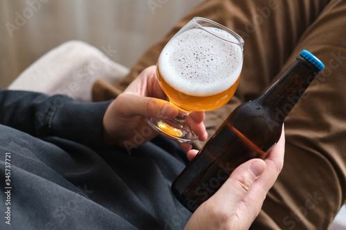 A glass of beer and bottle in the hands of a man. Tasting brewed craft beer. Lager beer with beautiful foam. Cold refreshment beverage. Alcohol drink. Relaxation and enjoyment on beer degustation