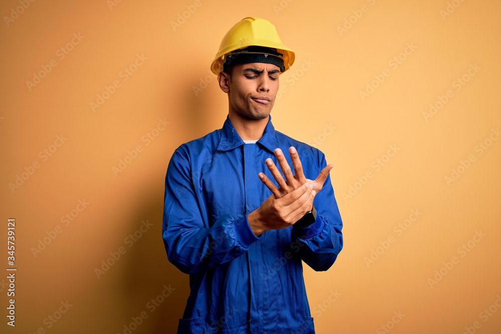 Young handsome african american worker man wearing blue uniform and security helmet Suffering pain on hands and fingers, arthritis inflammation